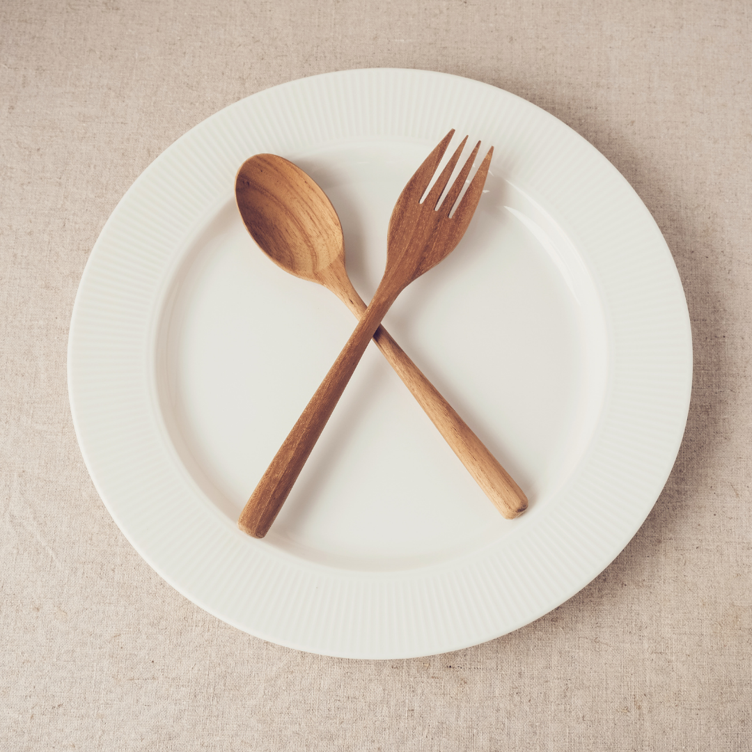 how to get started with fasting. empty plate and wooden utensils